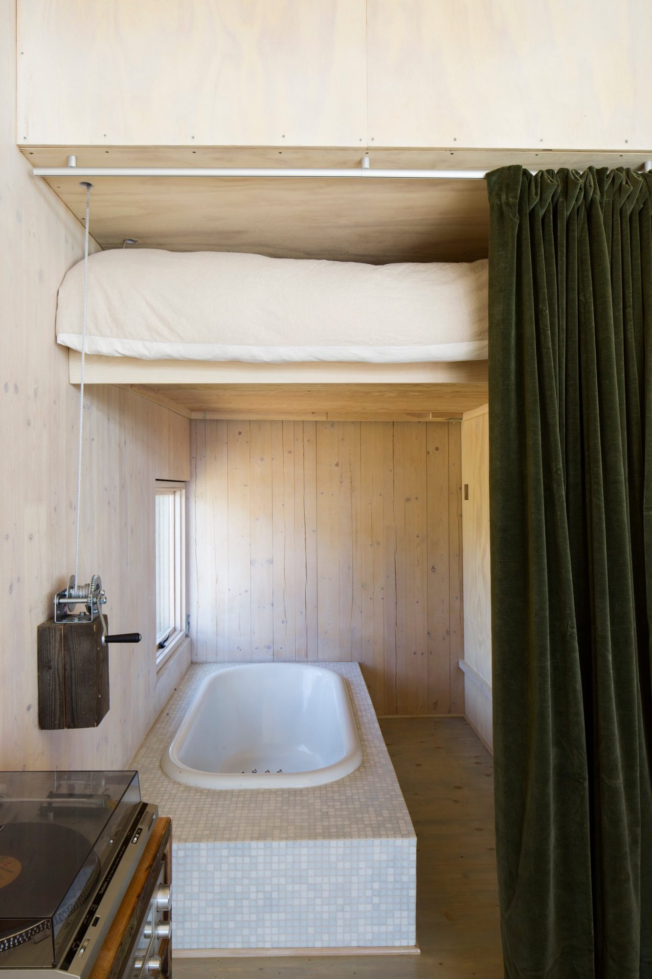 Bed raised on cables above a sunken tiled tub