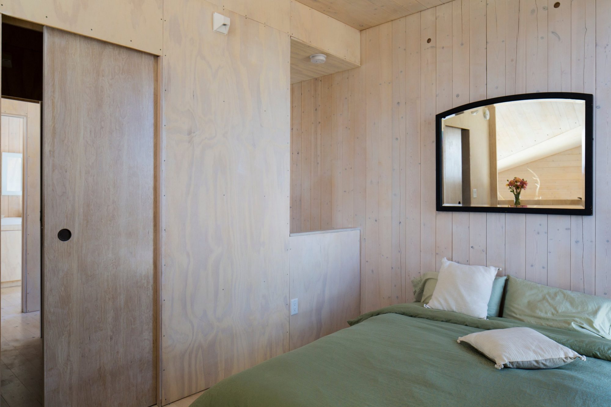 Loft bedroom with whitewashed timber walls and a green bedspread