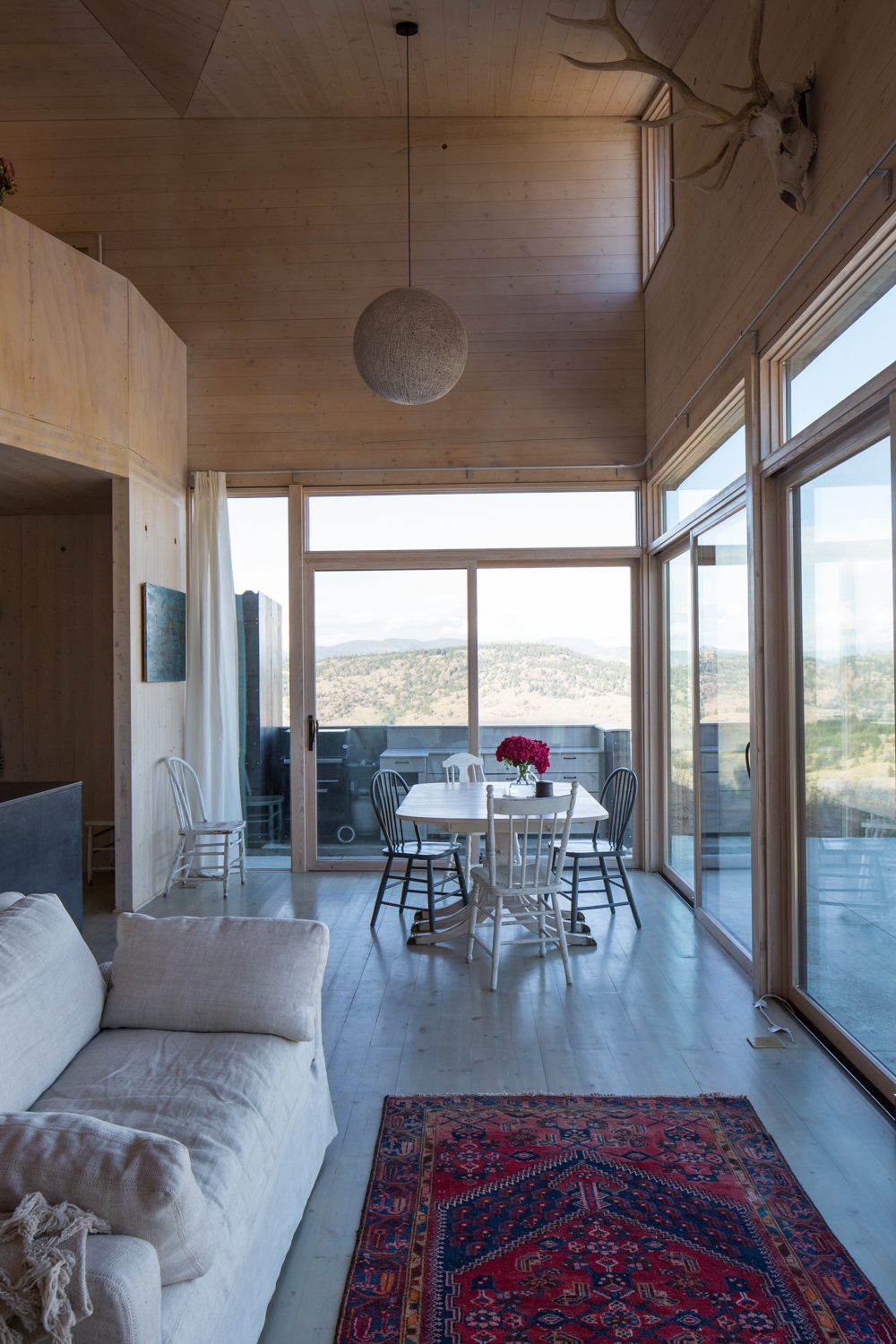 Dining table beside floor-to-ceiling glass looking over the hills