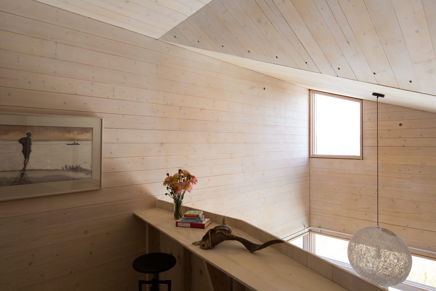 Built-in desk along the loft edge under a sloped timber ceiling