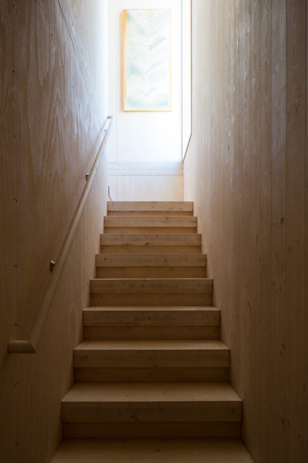 Narrow timber stair rising toward a window