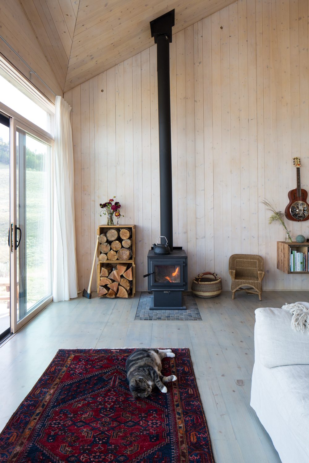Double-height living room with black wood stove and a red rug
